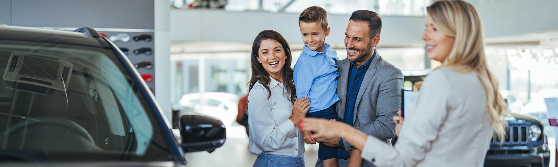 Dealership employee showing a couple a vehicle in the showroom