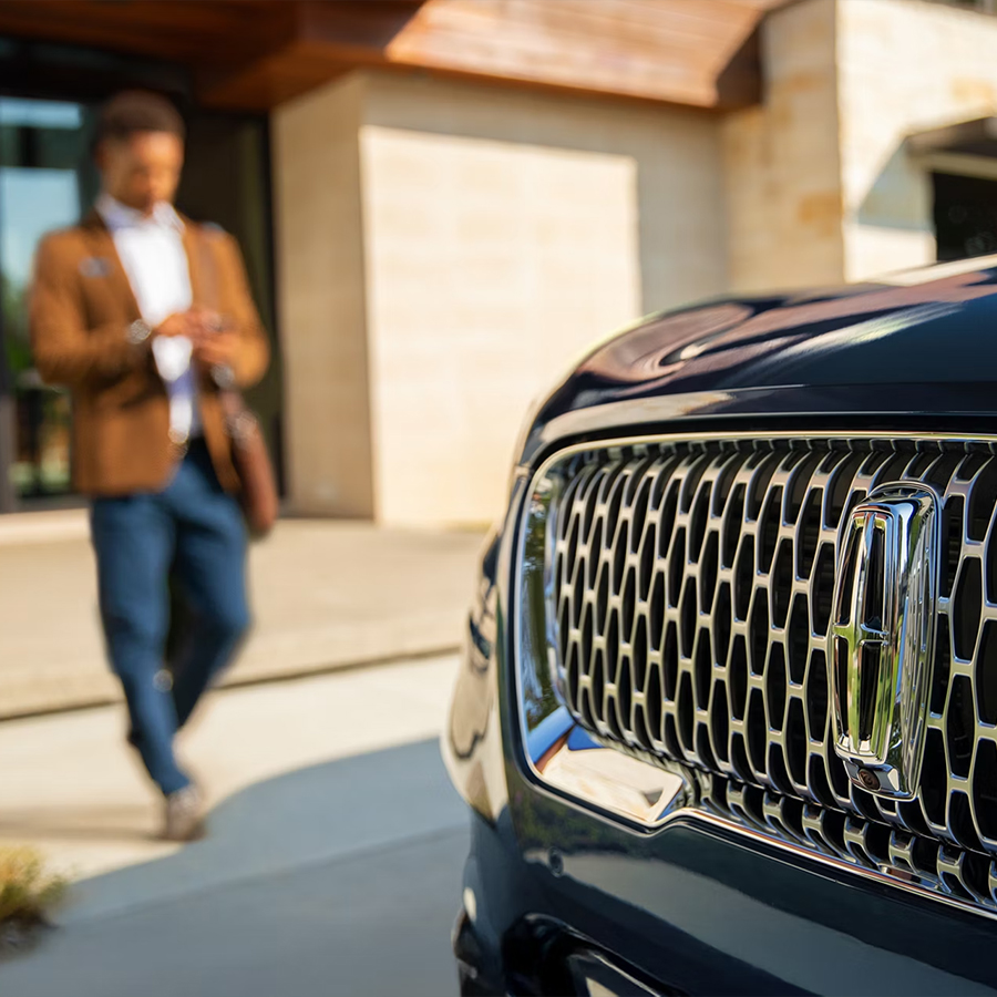 A man walking up to his Lincoln vehicle.