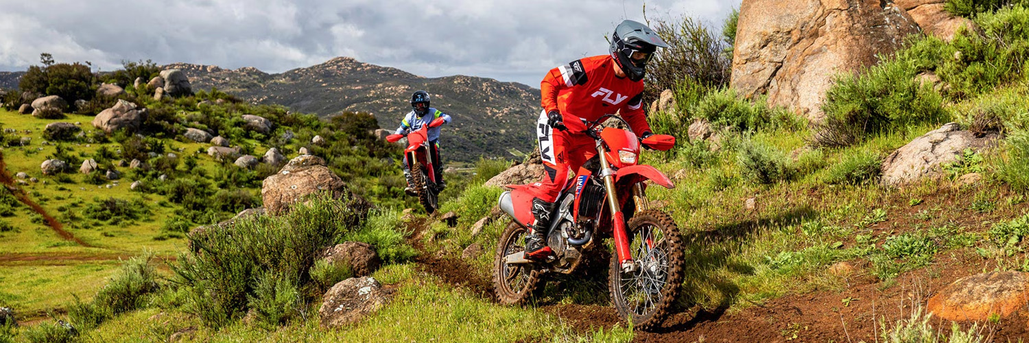 Two Honda Dirt Bikes shown riding through a hillside