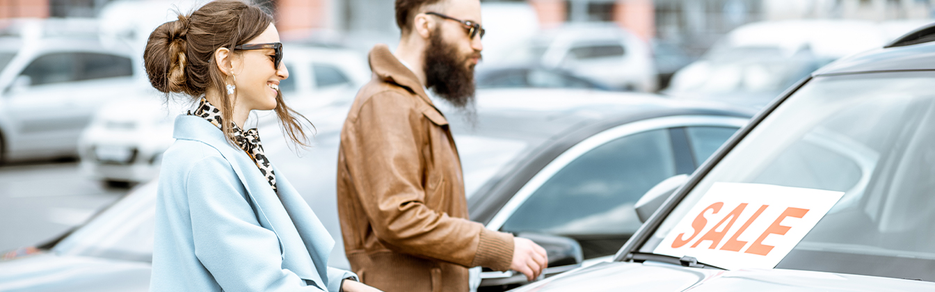 Dealership employee showing customers cars on showroom floor.