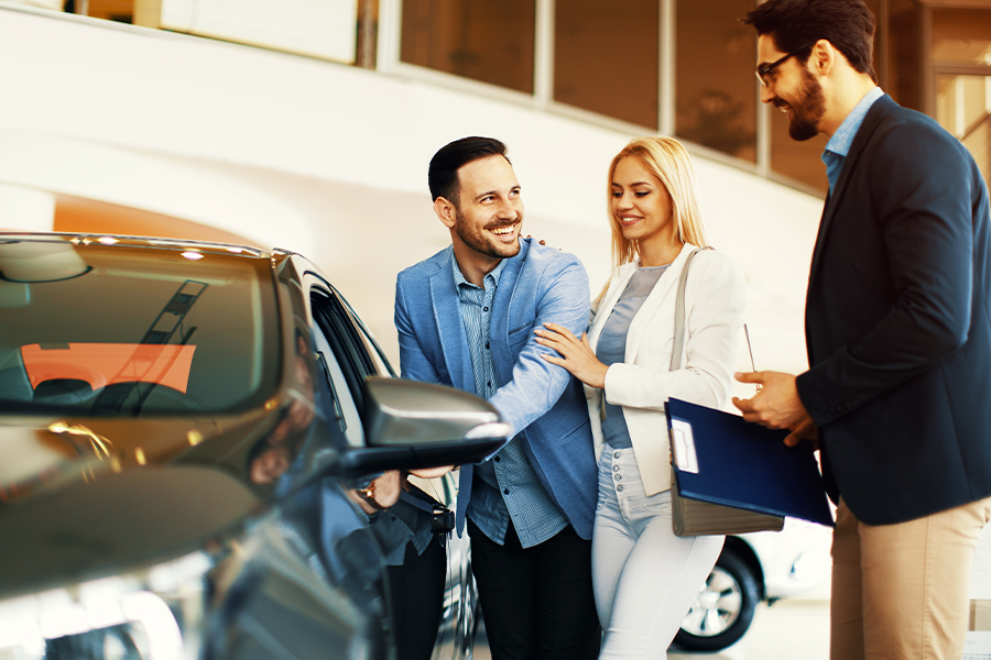 Young couple choosing new car for buying in dealership shop