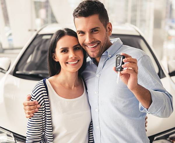 Couple smiling holding keys to their new car