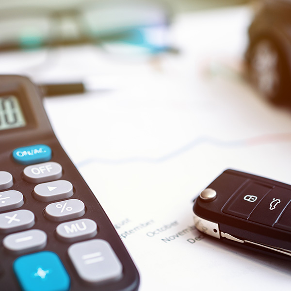 Close up shot of a calculator on budgeting paperwork and car keys off to the side