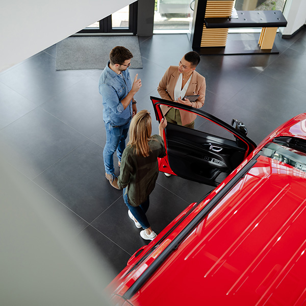 Top view of young couple choosing and trying new car in a showroom