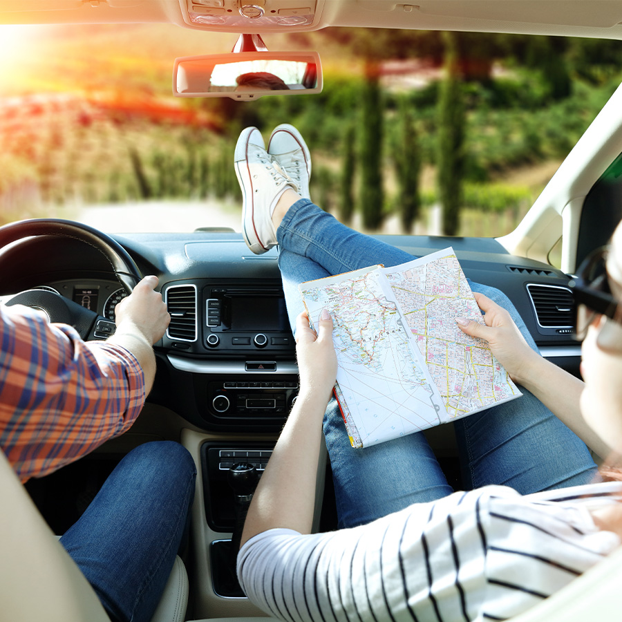 Person with feet on dashboard of car looking at map