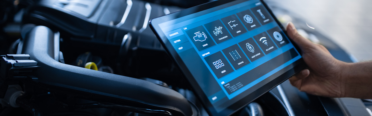 Auto technician looking at tablet diagnosing vehicle
