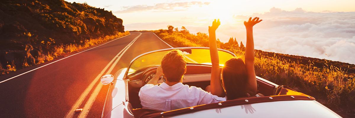 People driving down winding road during sunset