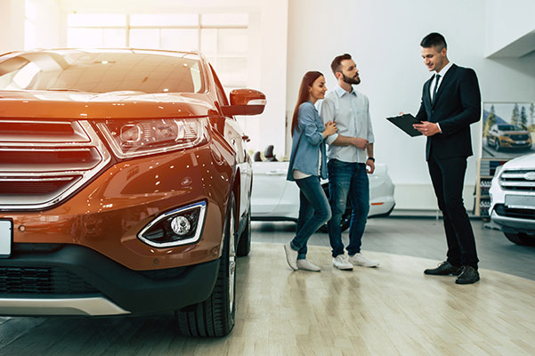 Salesman with couple looking at cars