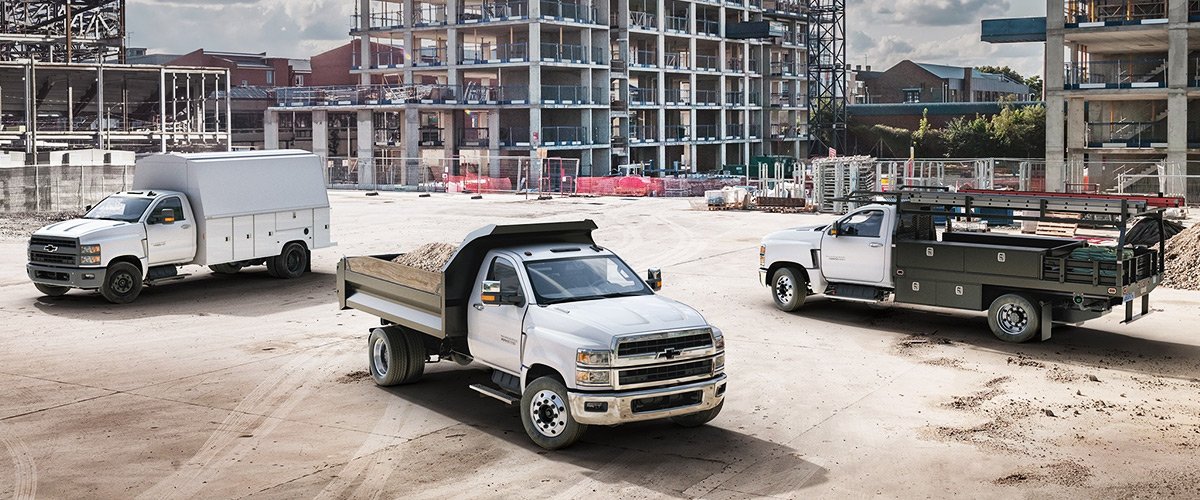 Lineup of Chevy trucks with mountains in the background