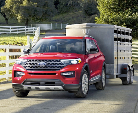 A 2022 Ford Explorer King Ranch® parked near a stable with a horse trailer attached