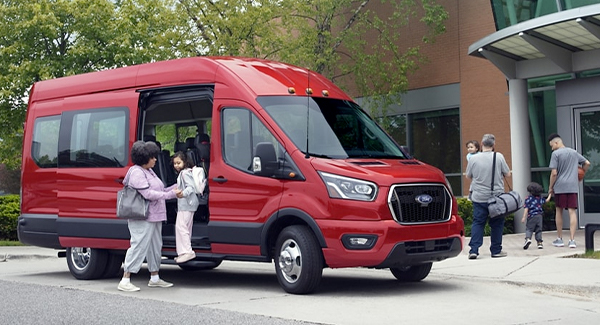 Two people getting out of a 2022 Ford Transit near a community center