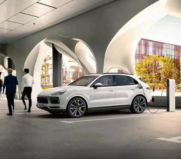 Businessmen walking past a Porsche Cayenne in a parking garage