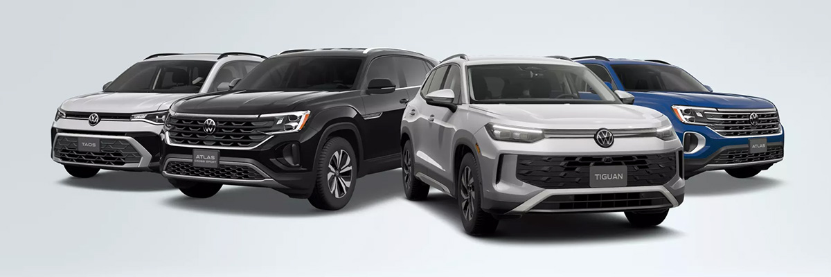 A Taos shown in Pyrite Silver Metallic, an Atlas Cross Sport shown in Deep Black Pearl, a Tiguan shown in Pyrite Silver Metallic and an Atlas shown in Mountain Lake Blue Metallic are parked together on a white gradient background.