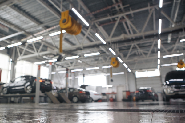 Blurred image of service shop with cars in background and on lifts