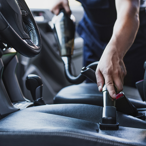 Person vacuuming interior of vehicle detailing