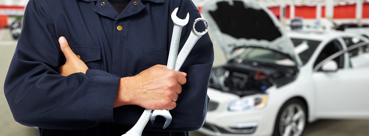 Service mechanic with tools and car in the background