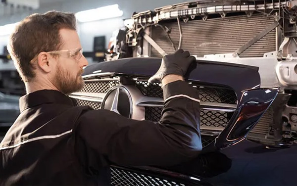 Mercedes-Benz service technician working on front of Mercedes car