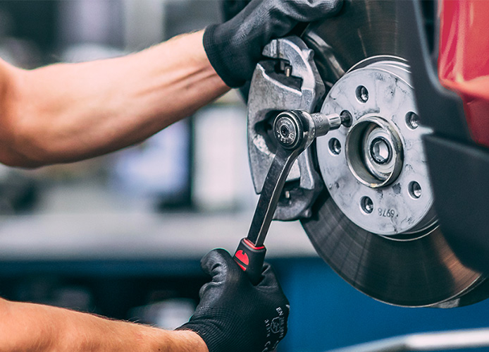 Male MINI Service Technician performs a brake service on a MINI vehicle in a MINI Service Facility.