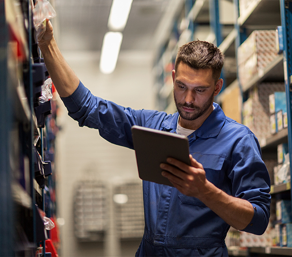 Auto mechanic looking at parts on shelves.