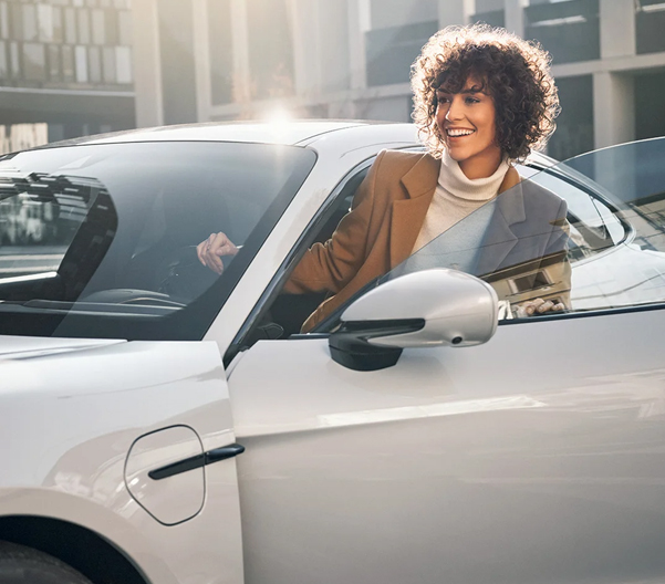 A woman partially outside of a Porsche car.