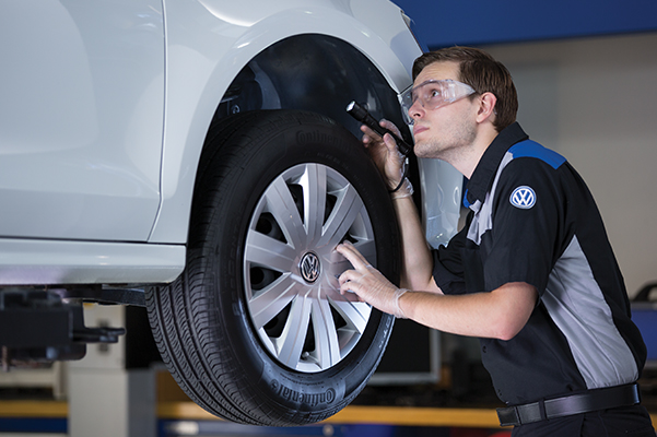 car service person looking at the wheels on a car