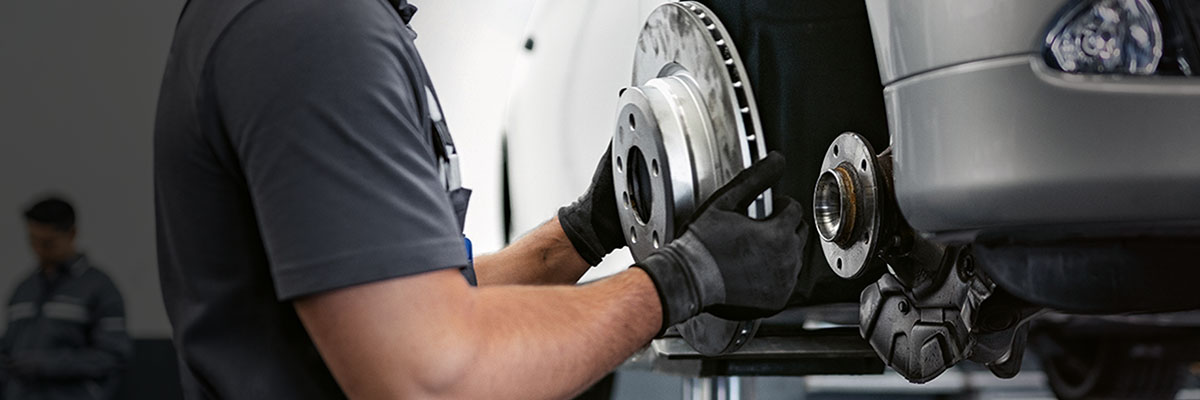 BMW Service Technician performing a brake disc change for a BMW vehicle on a lift in a BMW Service Center.