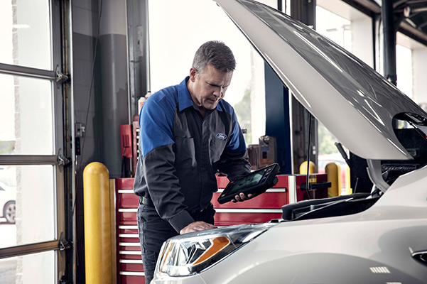 Ford mechanic running a test on a vehicle with an opened hood