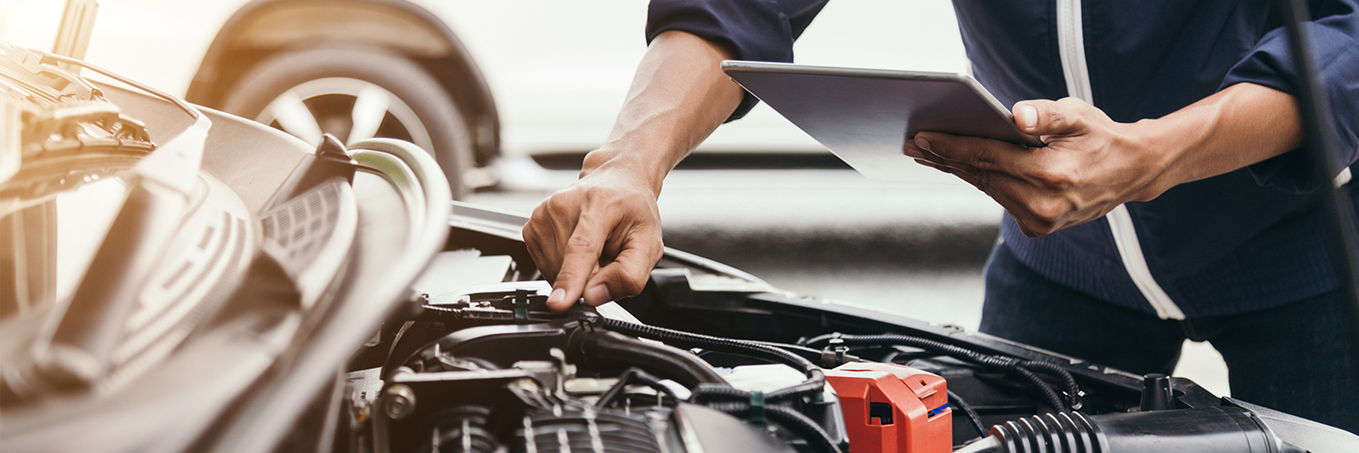 Up close shot of technician diagnosing vehicle with checklist