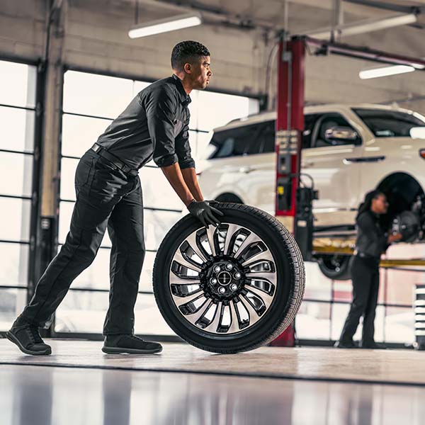 Technician rolling wheel across service room floor
