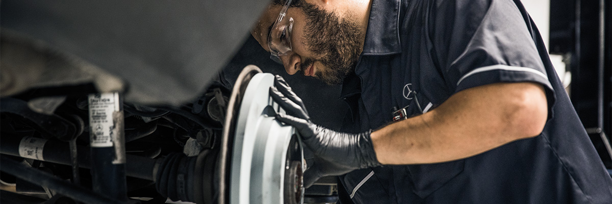 Up close shot of Mercedes-Benz technicians working on brakes of vehicle
