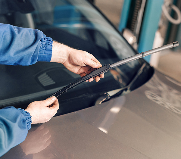 Mechanic inspecting car exhaust on lift with clipboard