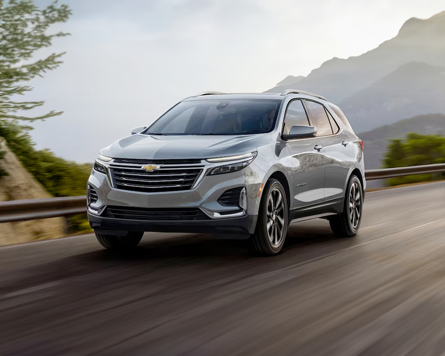 2024 Chevy Equinox driving down a road with mountains in the background