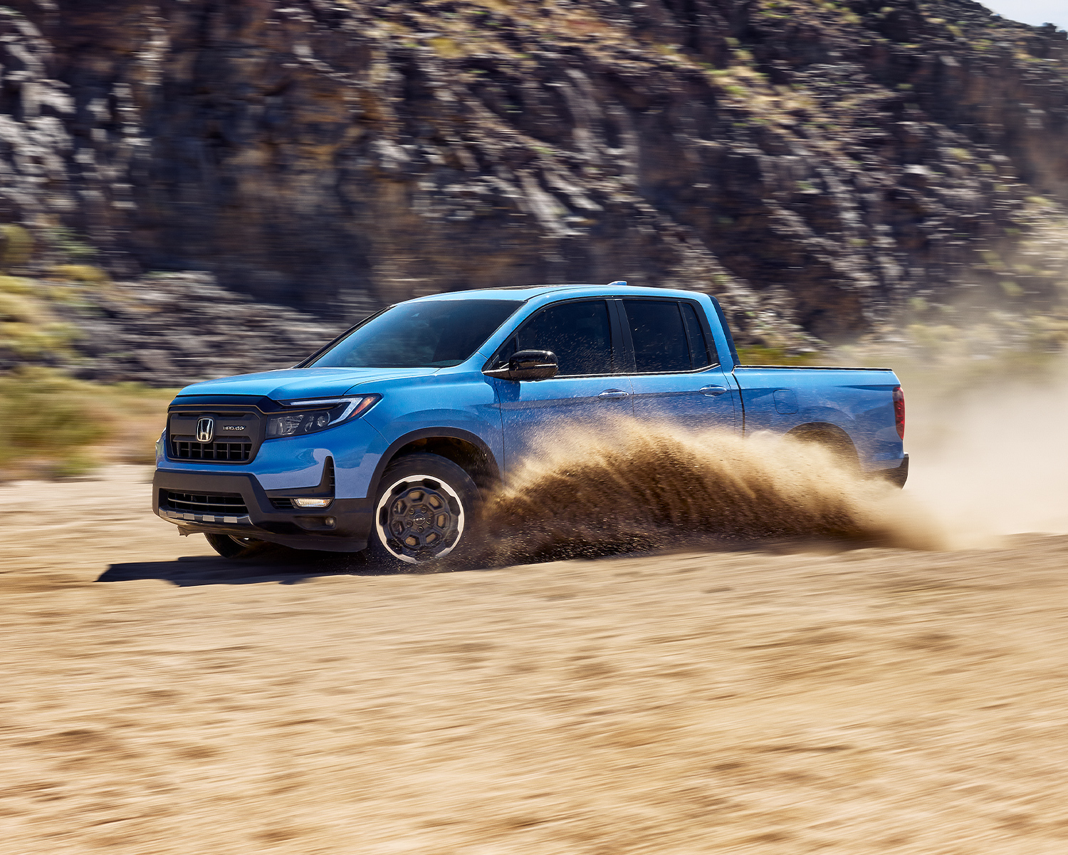 2024 Ridgeline driving through the desert picking up sand with mountains in the background