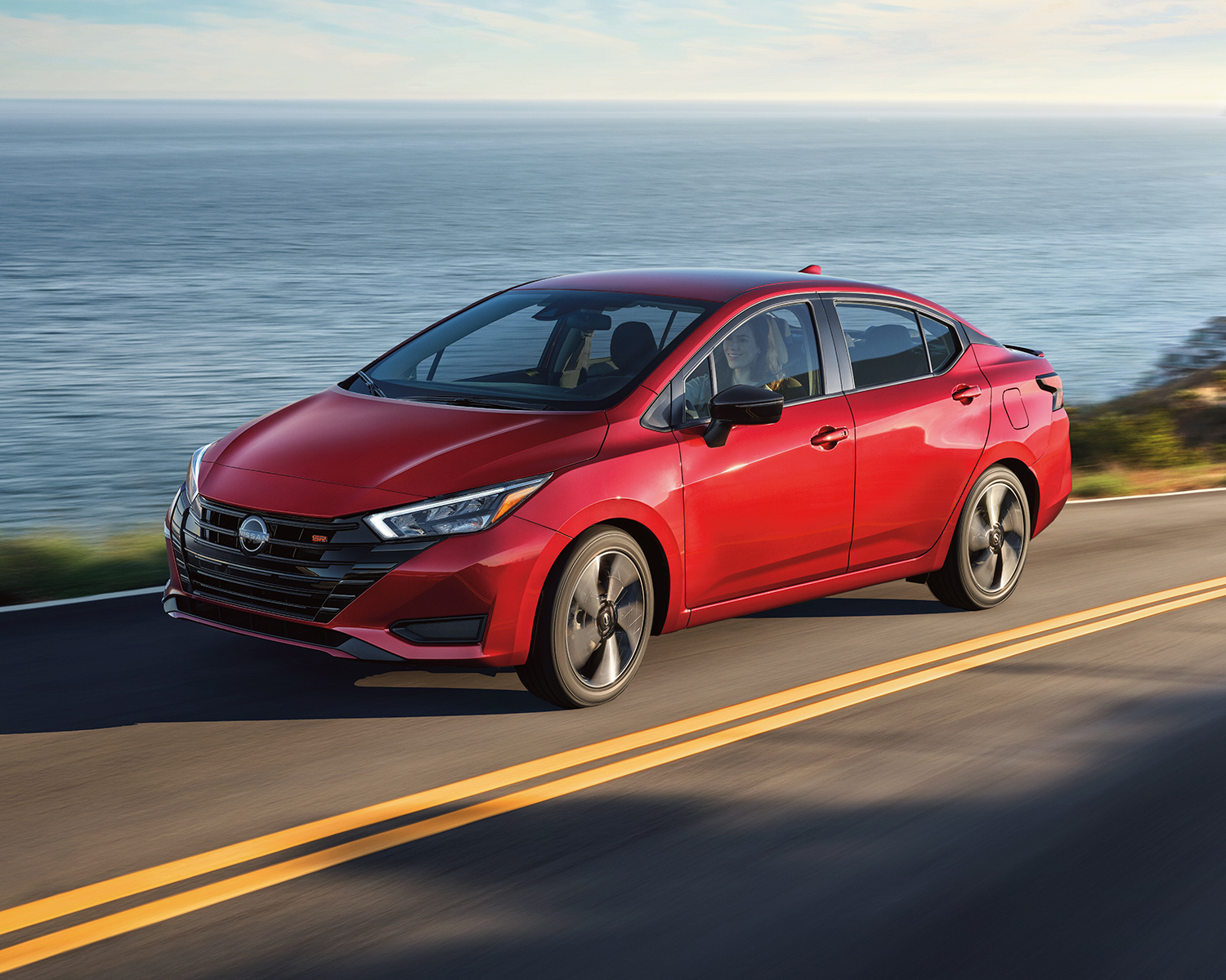 A 2024 Nissan Versa driving on a coastal road