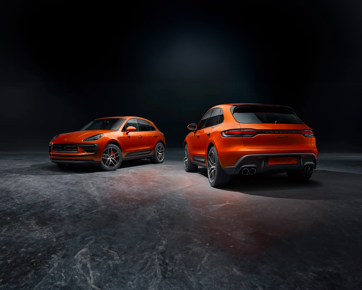 Two Porsche Macan vehicles parked in a dark lot
