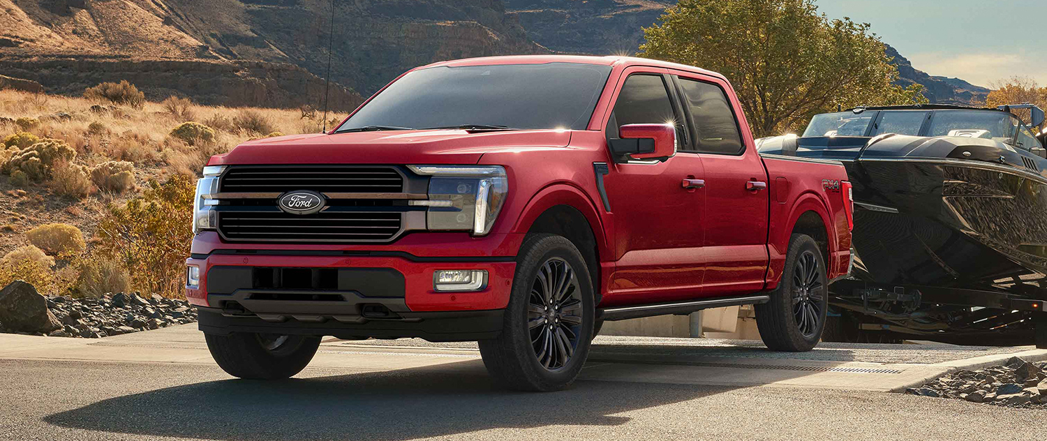 Red 2025 F-150 towing a boat.