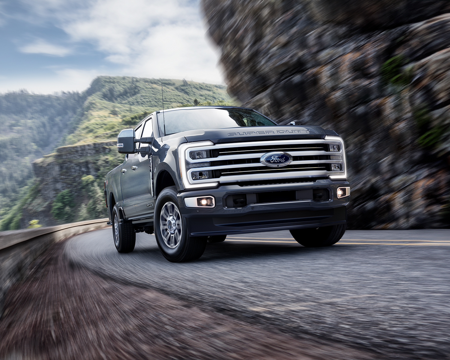 2025 Ford Super Duty driving around a winding road with mountains in the background