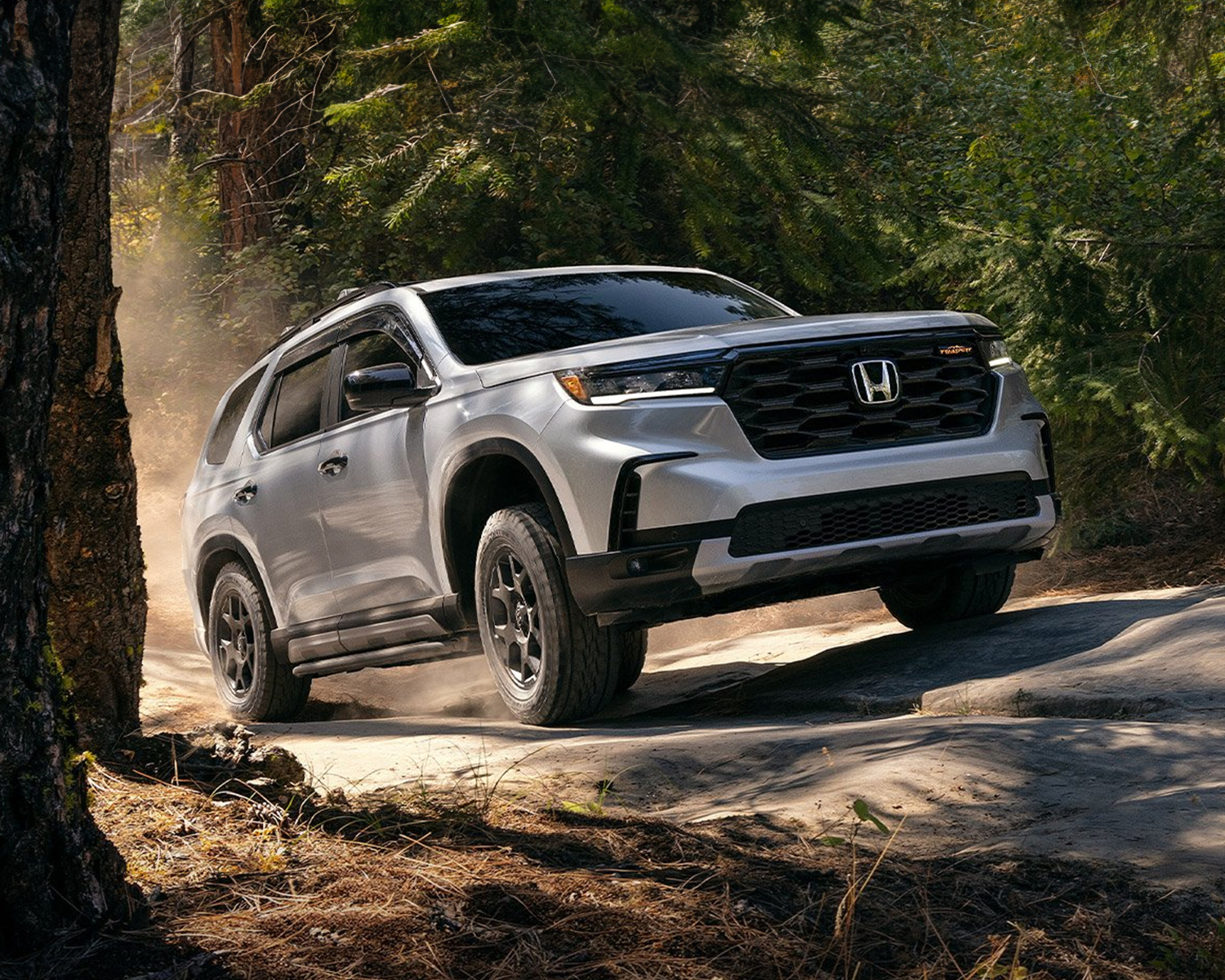 2025 Honda Pilot driving offroad through the woods