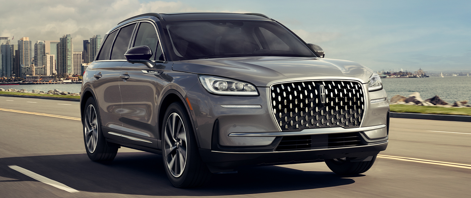 2025 Lincoln Corsair driving down the road with city skyline in the background