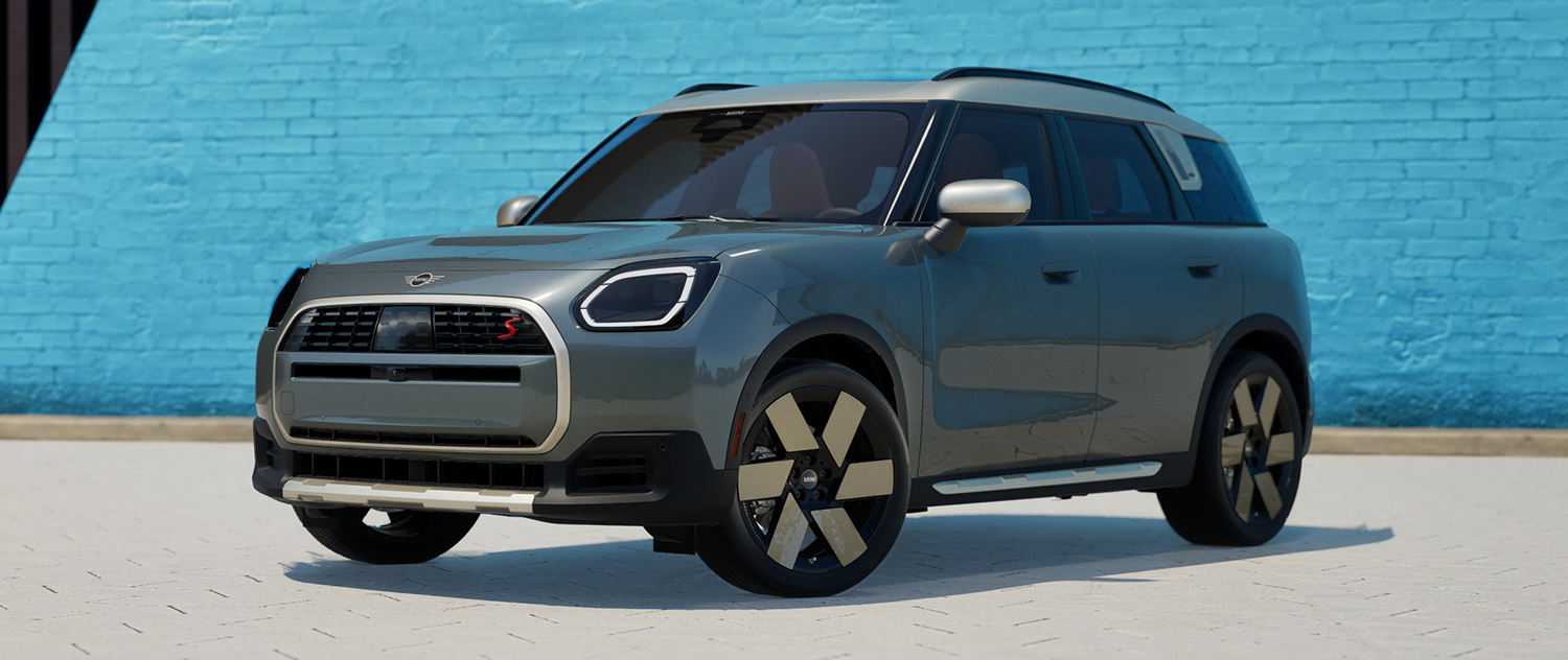 A 2025 MINI Countryman parked in front of a blue brick wall.