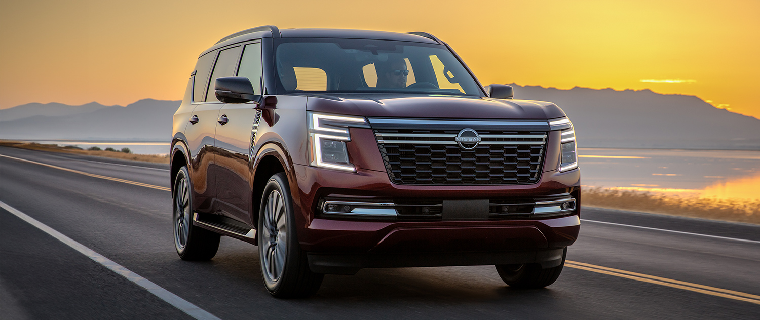 2025 Nissan Armada driving down the street with mountains in the background