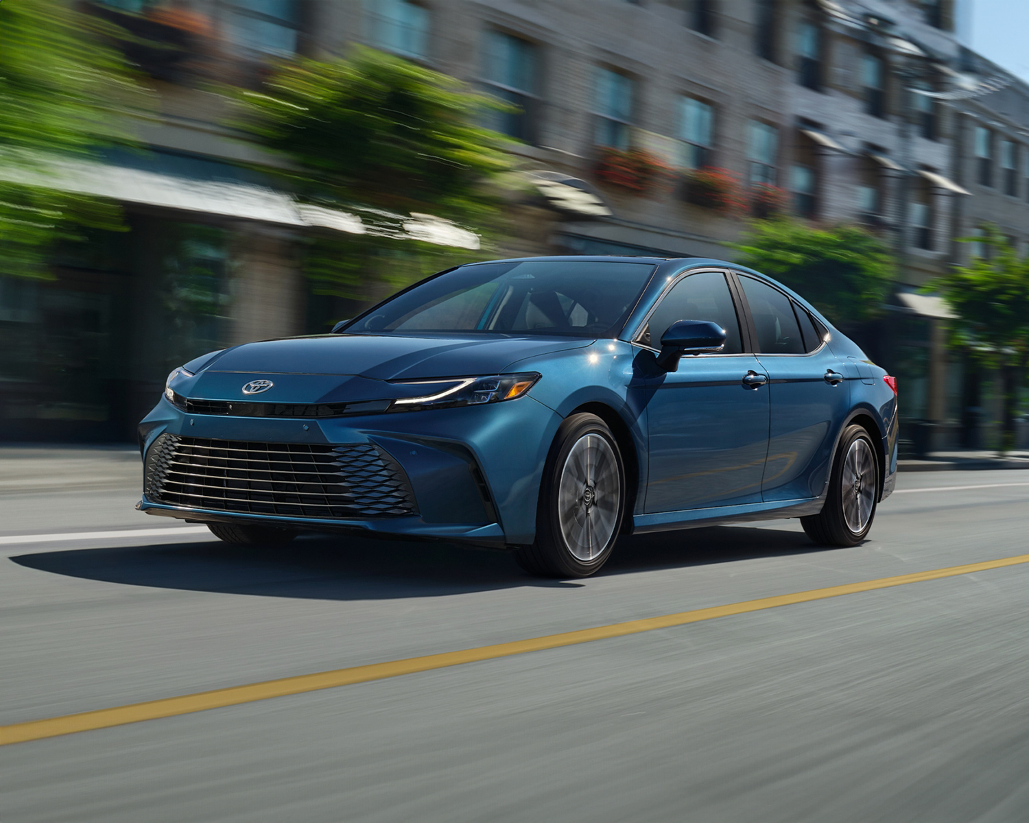 The 2025 Toyota Camry driving down the street of a local town