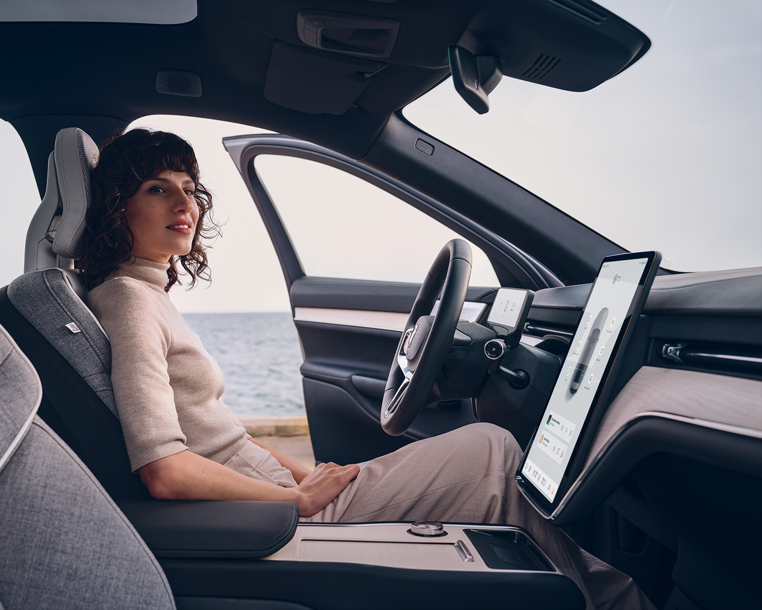 Interior shot of a woman sitting in the drivers seat of her new Volvo EX90 while parked at a beach