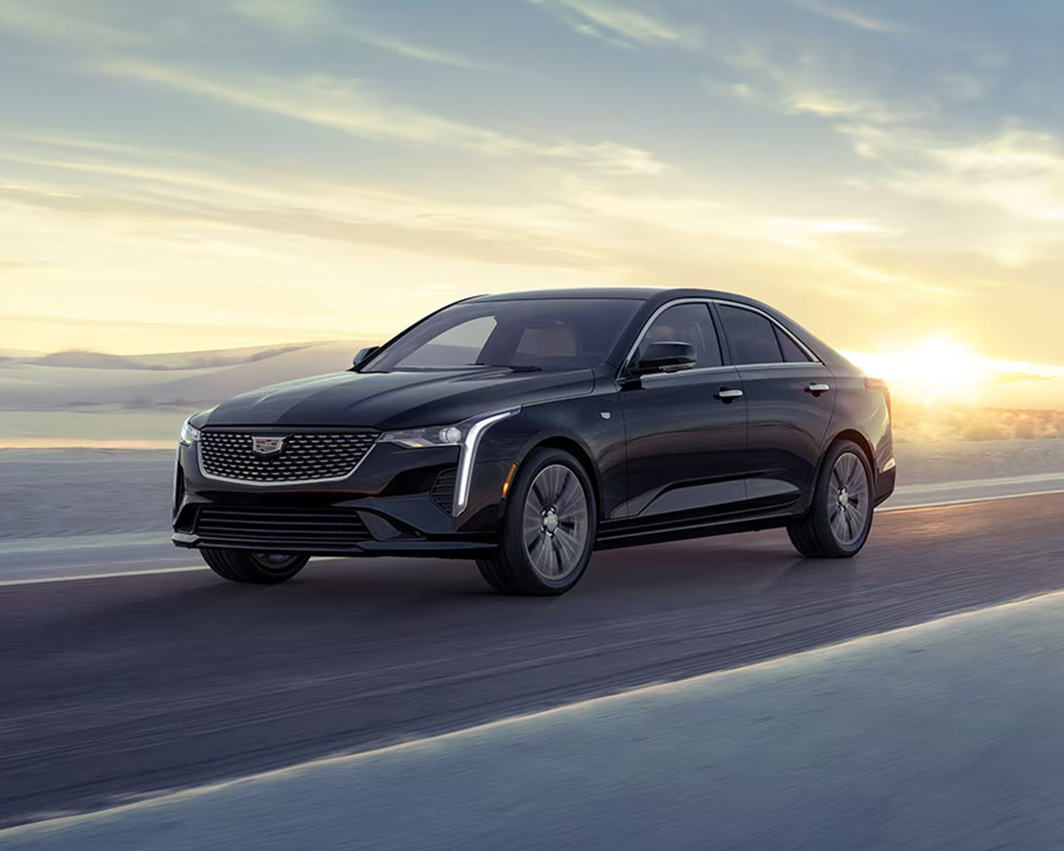 2026 Cadillac CT4 driving down the road at sunset