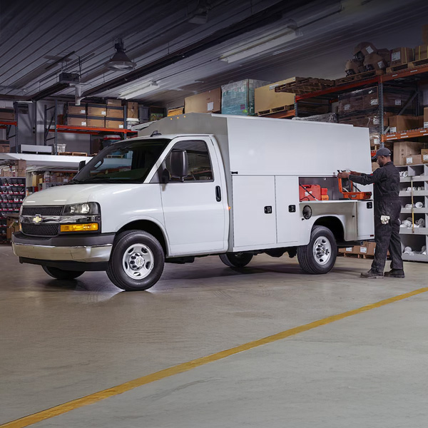 Man Storing Work Equipment in Exterior Storage Compartment on His 2026 Chevy Commercial Express Cutaway