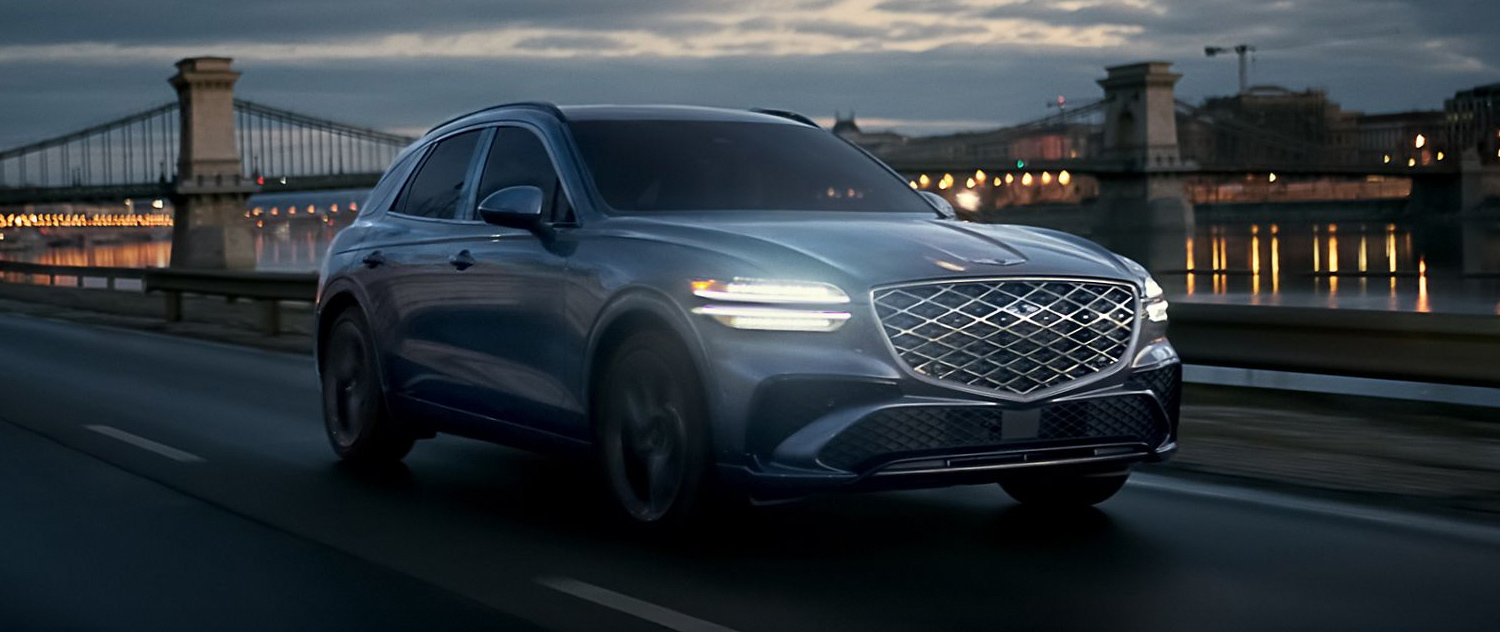 Genesis GV70 driving on a city road at night