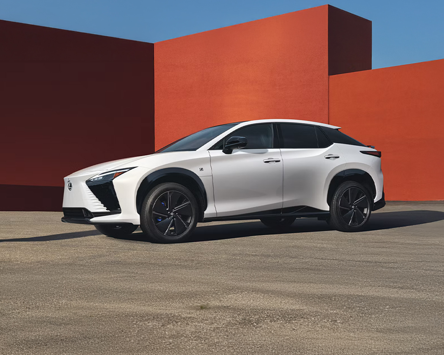 2026 Lexus RZ side view, parked outside a modern structure outside
