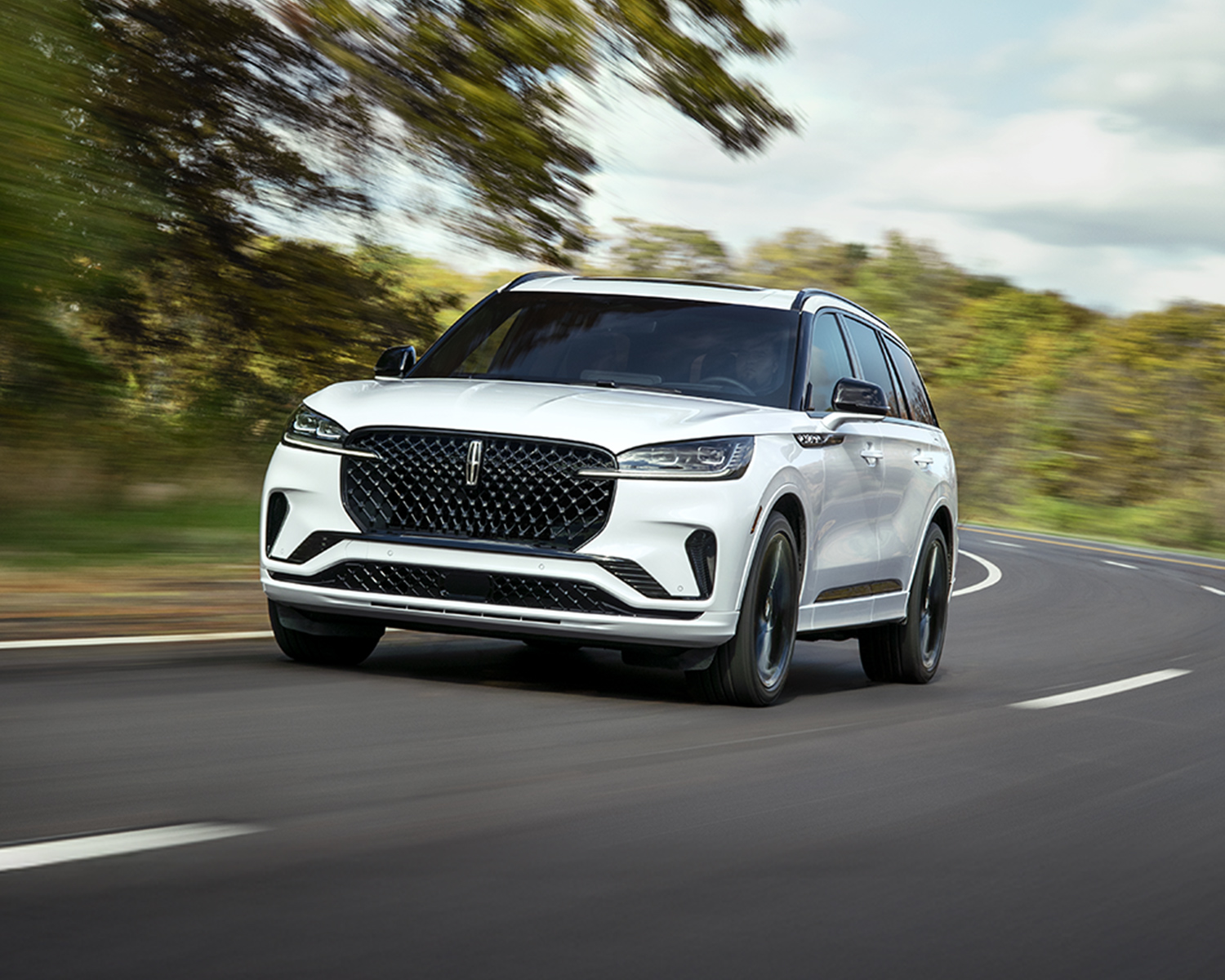 2026 Lincoln Aviator on a winding road with trees in the background