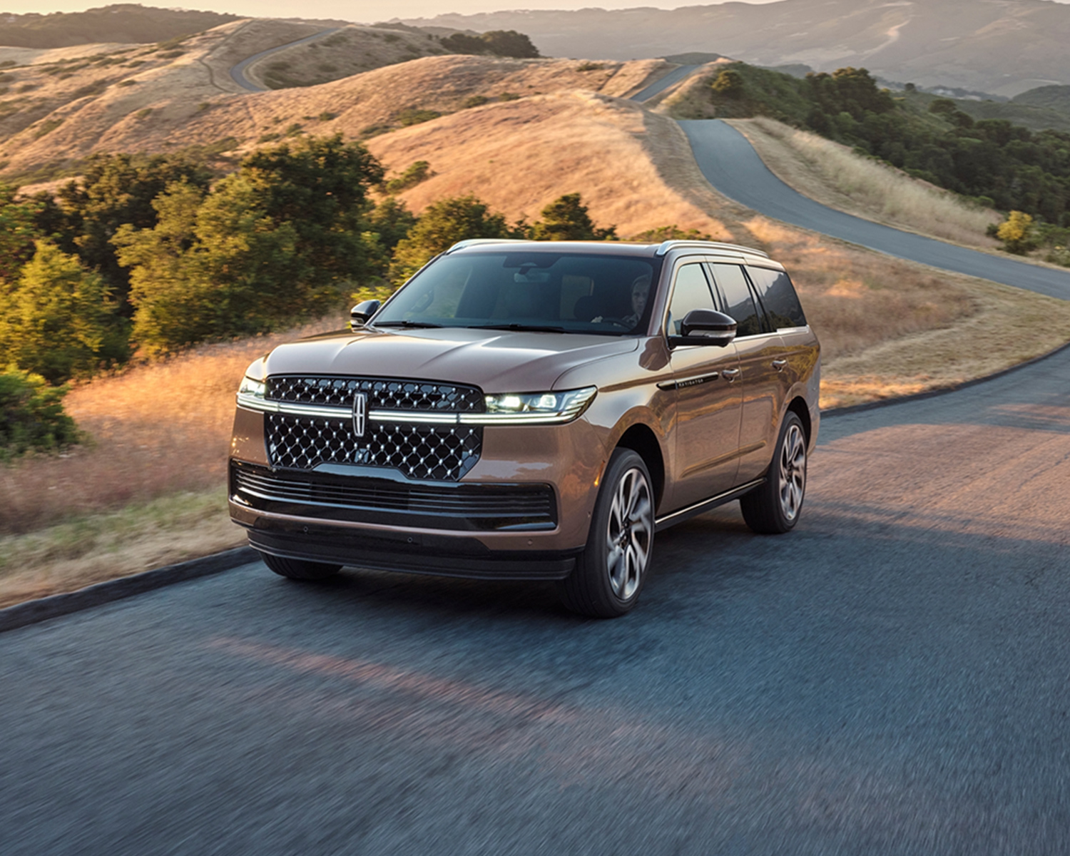 2026 Lincoln Navigator driving on a road with mountains shown