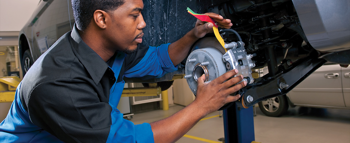 View of a service professional checking the brakes of a car for wear.